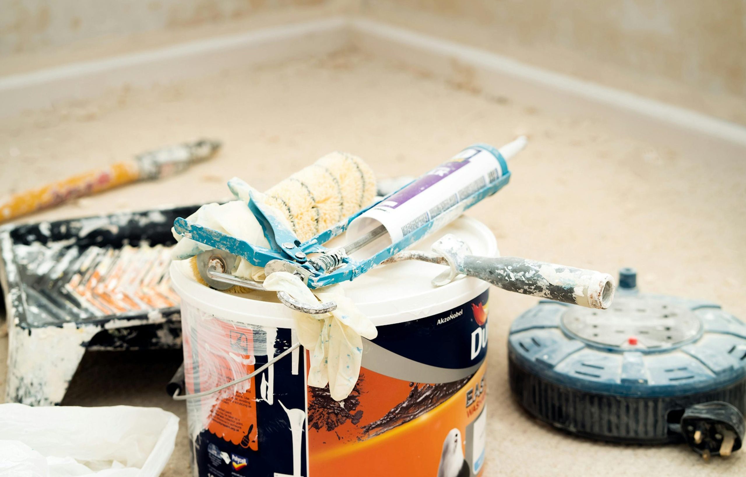 A collection of painting tools and materials for home renovation, featuring paint rollers and a bucket.